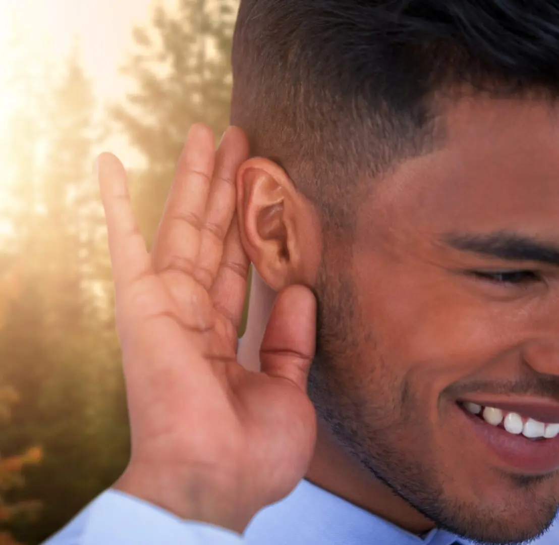 A man with his hand up to the side of his ear.