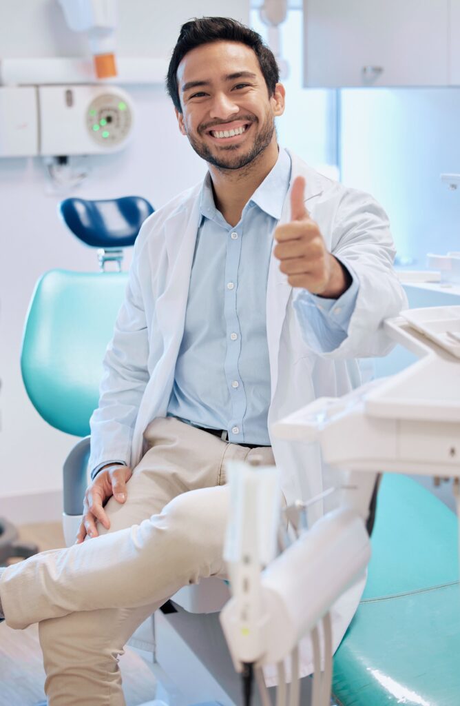 A man in white coat sitting on chair near table.