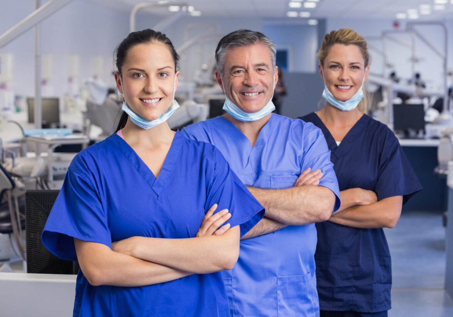 Three doctors standing in a row with their arms crossed.